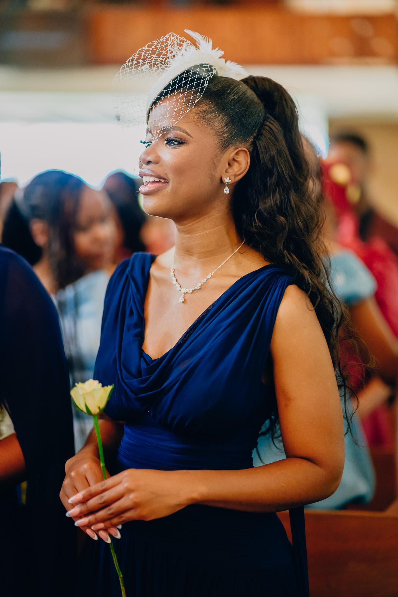 Guest in a navy dress holding flowers in church.
