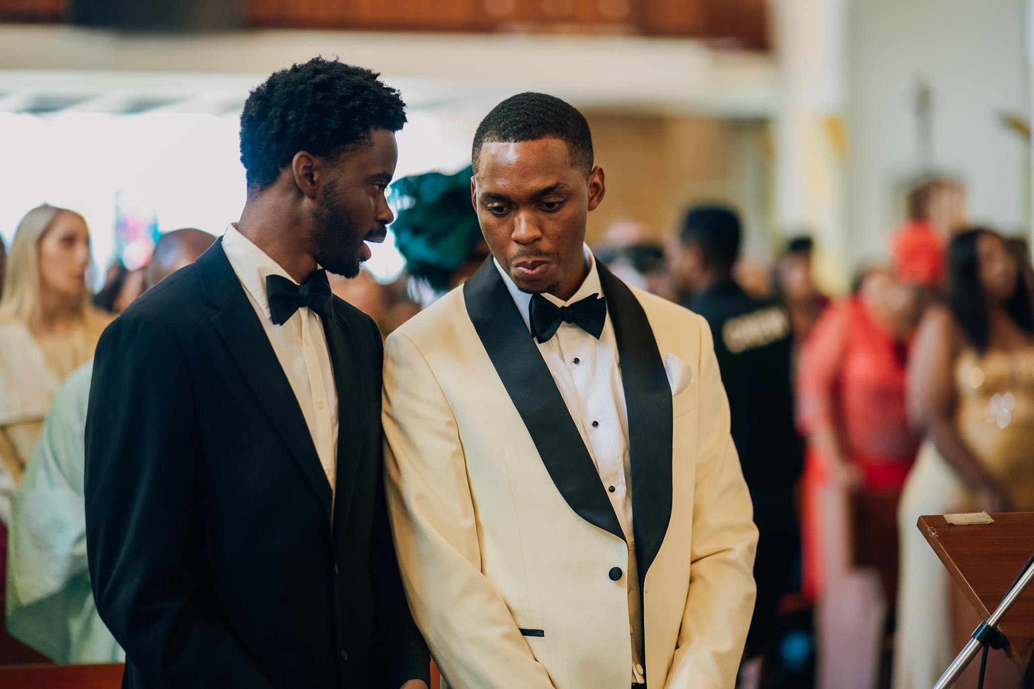 Groom standing beside a guest during the church service.