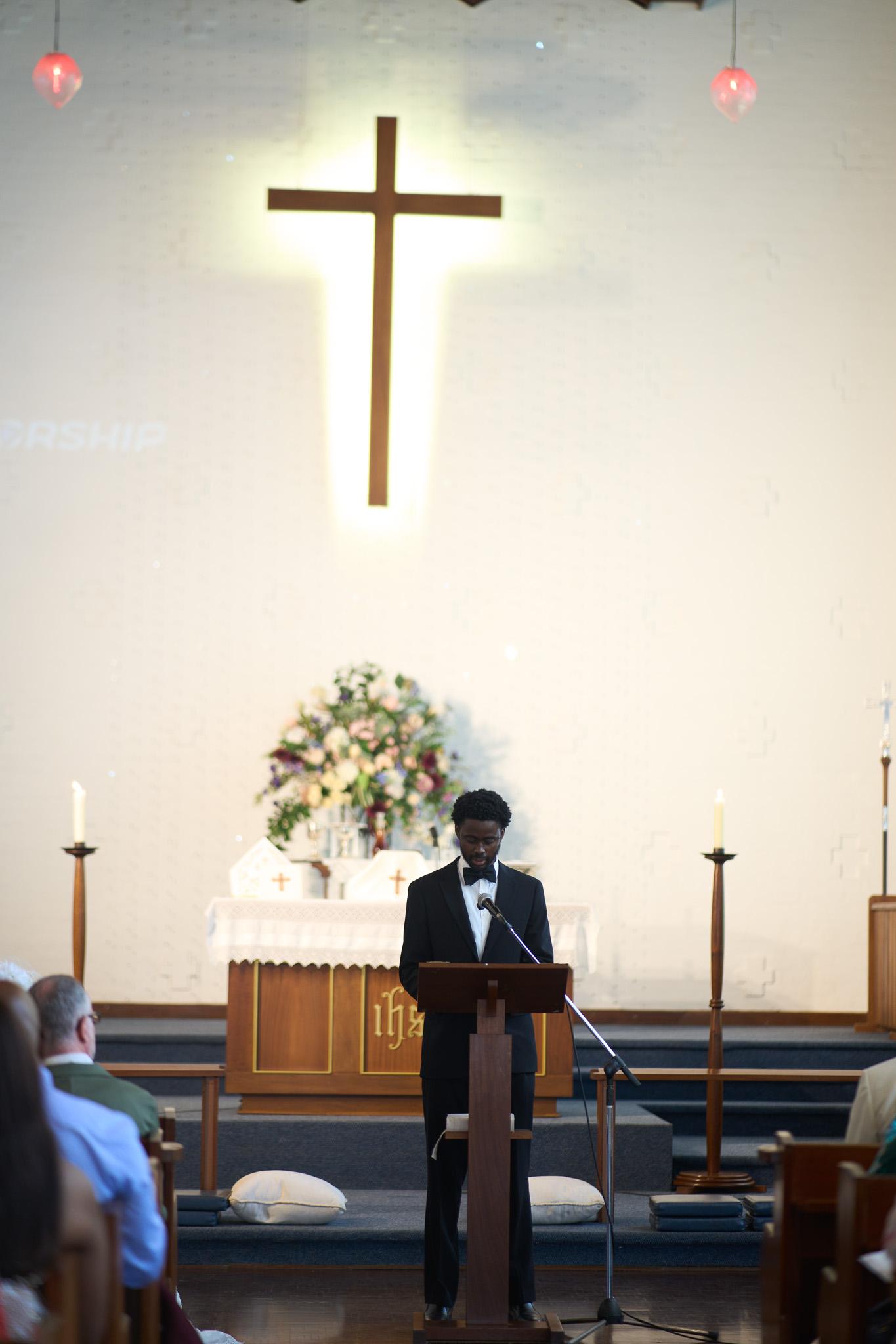 A speaker at the church lectern beneath a cross.