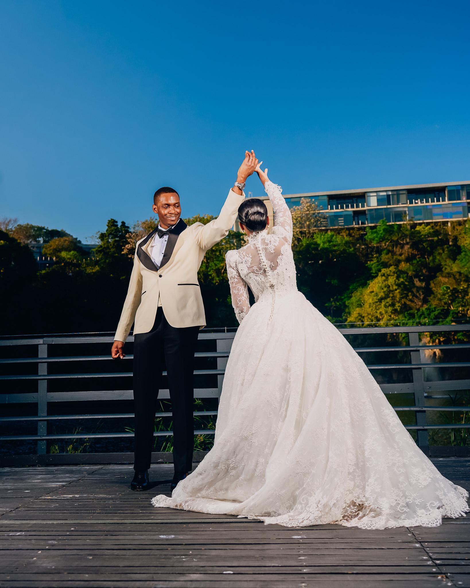 Groom raising the bride’s hand as they dance on the terrace.