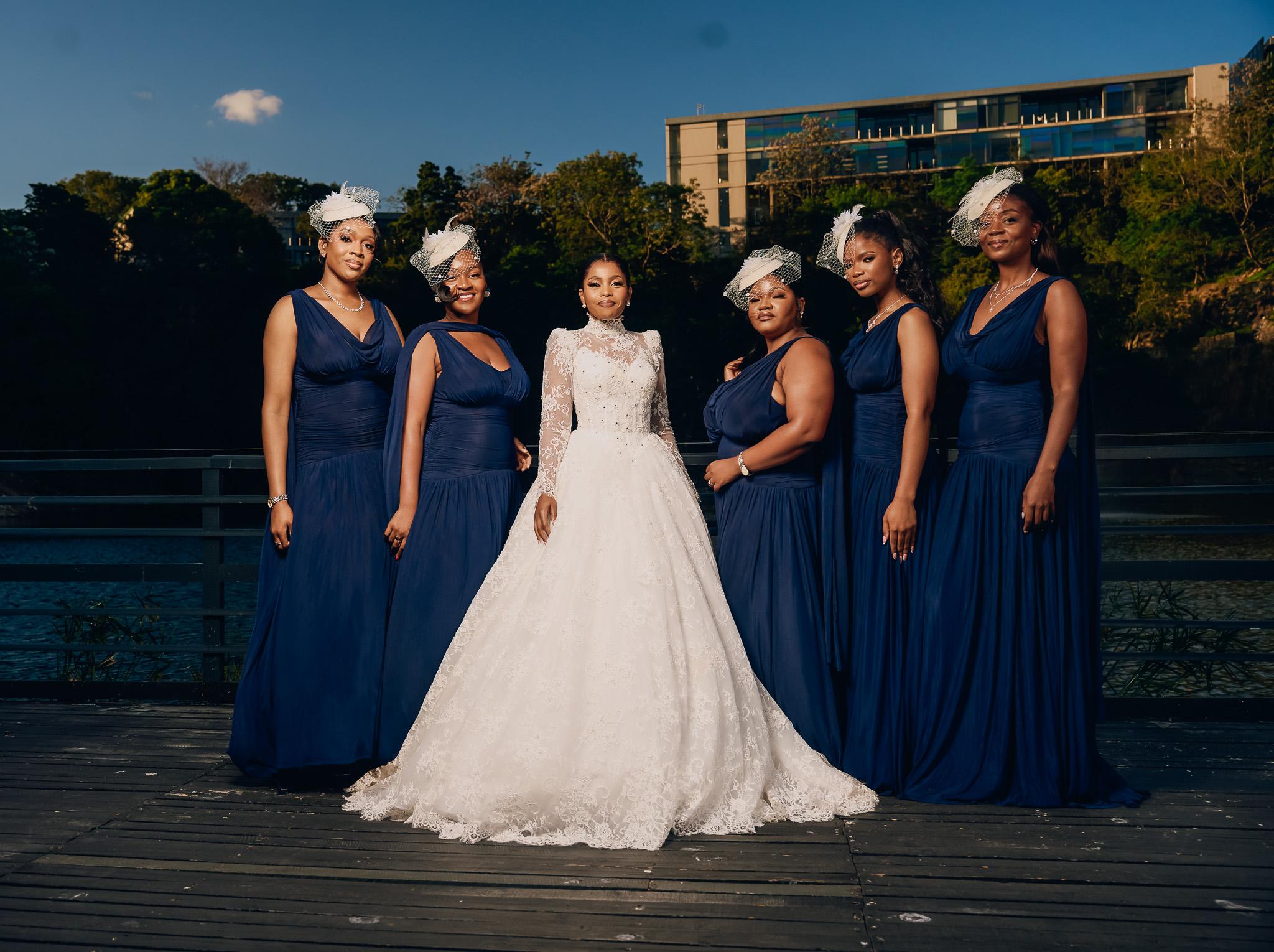 Bride with guests in navy dresses on an outdoor terrace.