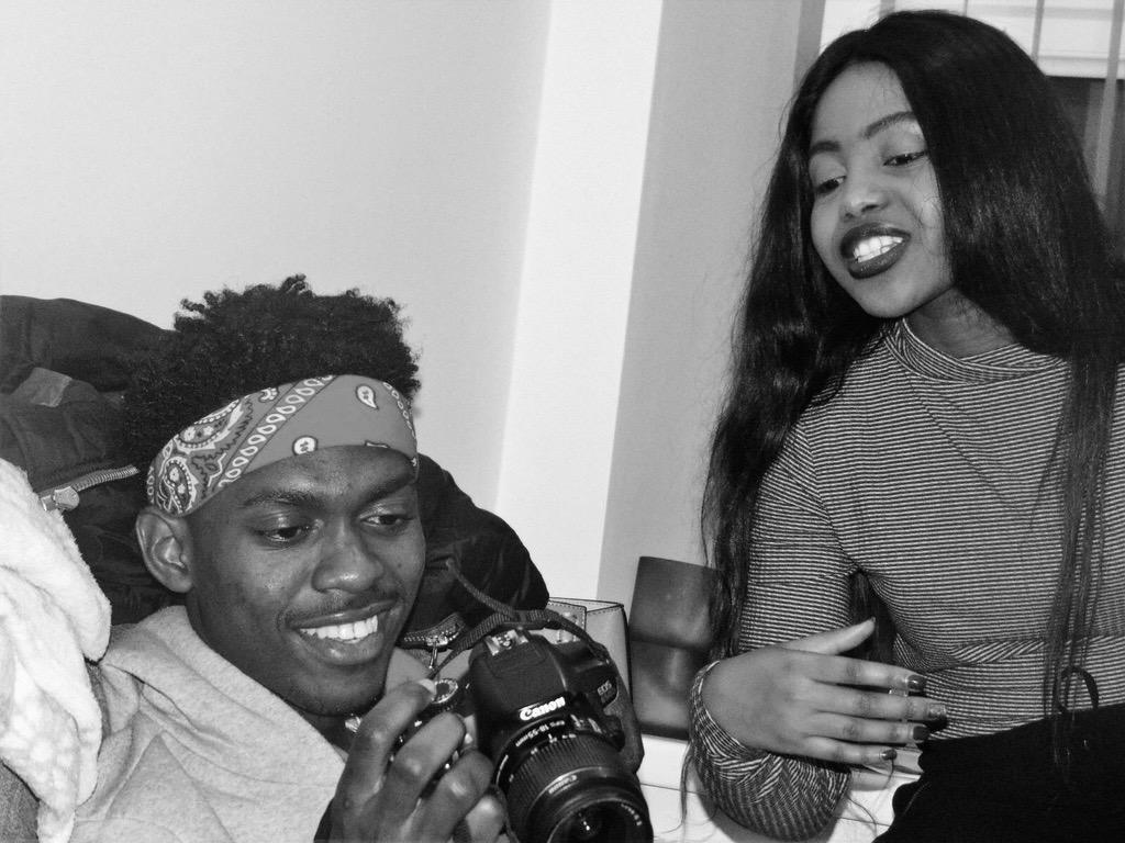 Afifoluwa and Mihlali laughing together in an early candid moment, a camera in his hands, in black and white